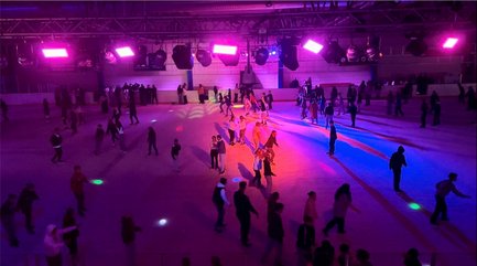 Menschen beim Eislaufen zu Discobeleuchtung